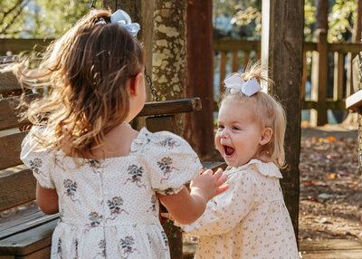 Two sisters laughing together during a family session at Hopelands Gardens in Aiken SC.