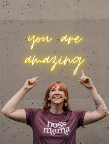 Redhead lady pointing to a sign that says "you are amazing"