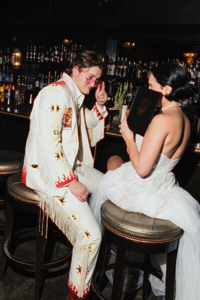 A joyful couple reviewing their wedding album together, capturing the satisfaction and cherished memories preserved through Ember's lens, as echoed in client testimonials.