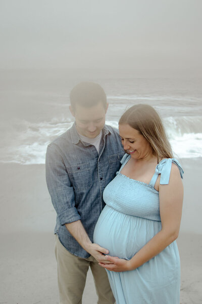 Expecting parents holding the baby bump on the beach