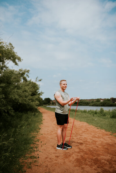 Natural light portrait of a man with a resistance band outdoors, showcasing an active lifestyle during an online dating photography session in Minneapolis.