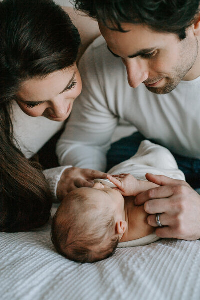 Newborn Photographer, couple looking at newborn baby lying on bed