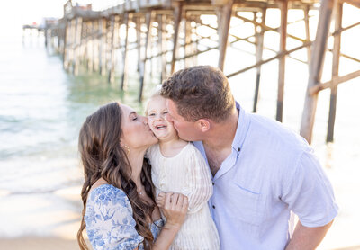 family photo of parents kissing daughter