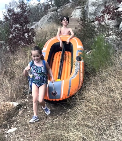 Young girl standing near an orange inflatable boat