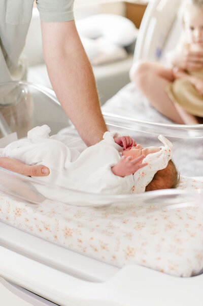 Dad picking up newborn baby girl hours after her birth during their family portraits