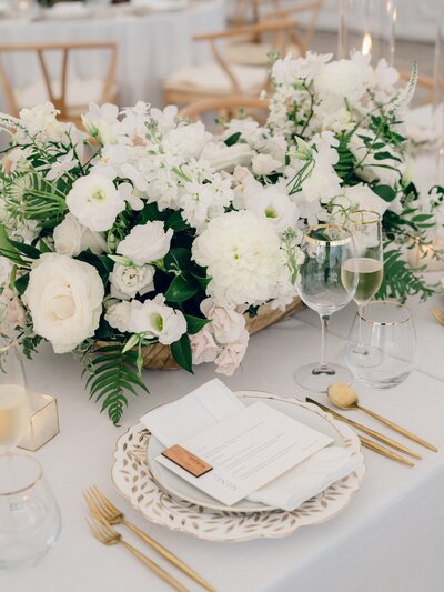 A bright and airy neutral wedding venue photo of the main dining area with brown chairs and white flowers during an alyssa amez design custom wedding