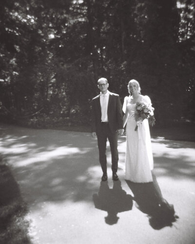 bride and groom holdings hands looking at the camera