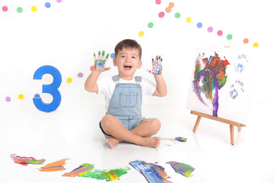 boy smiles while covered in paint at his 3rd bday photoshooot