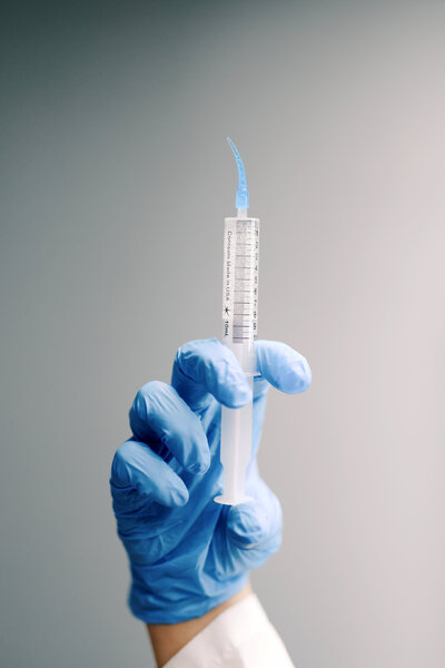 A close-up image of an injectable tooth-shaped device designed to dispense teeth whitening gel. The device resembles a tooth in shape and is filled with whitening gel, ready to be applied to the teeth. The gel is dispensed from a small opening at the tip, allowing for targeted and precise application. The tool is compact, ergonomic, and intended for professional or at-home teeth whitening treatments.