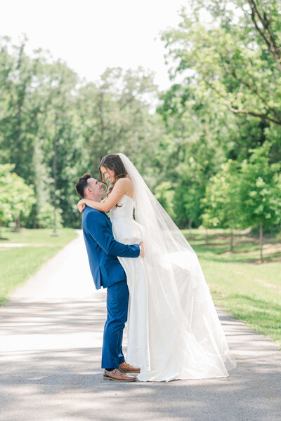 Groom lifting up bride and smiling at each other ina. park