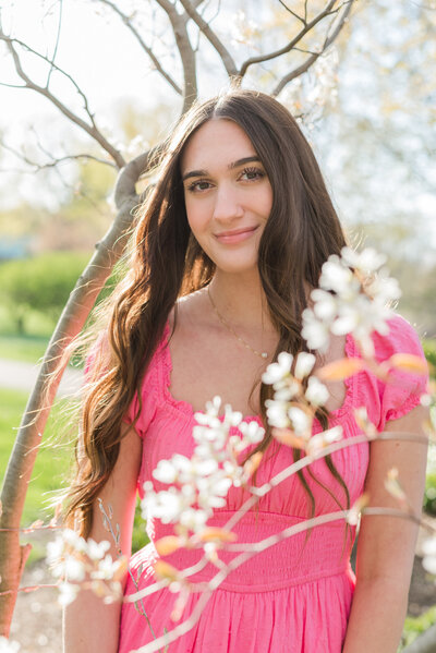 Close-up headshot of a senior girl surrounded by flowers.