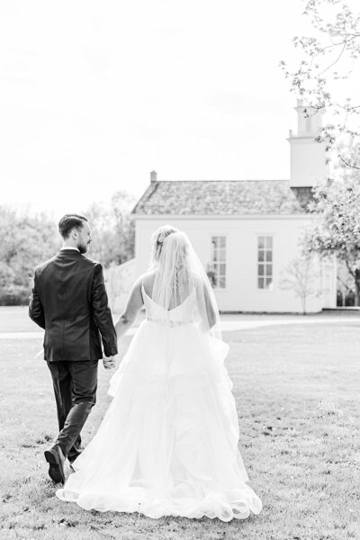 Bride and groom holding hands walking toward Goodells County Park Chapel