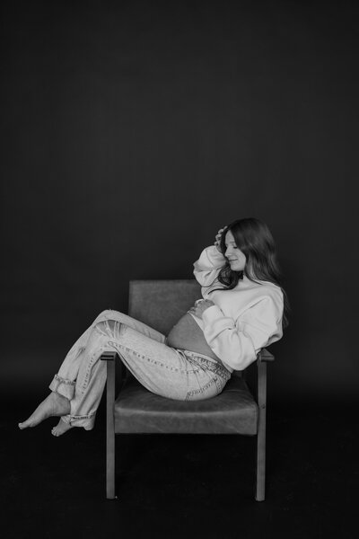 woman holding pregnant belly in field