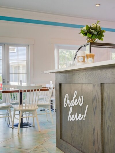 Interior shot of Sugar Bean coffee counter with ‘Order Here!’ signage, clean lines, natural light, and brand colors reflected in decor.

