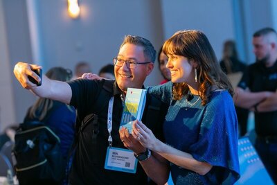 Brittany Hodak takes selfie with audience member, holding her book Creating Superfans