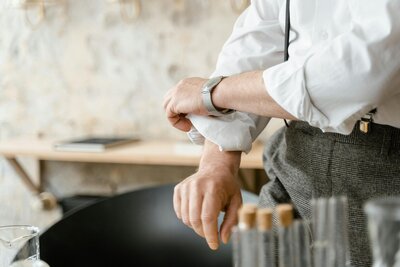 A white man rolls up the sleeve of his dress shirt