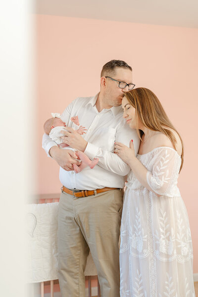 dad kiss mom’s head while holding baby at the nursery during Fauquier County, Virginia newborn photo