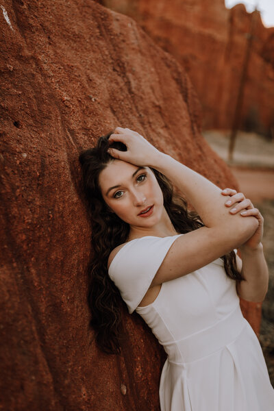 girl poses against red rock for her colorado photographer