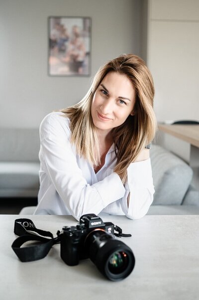 portrét fotografky, která sedí za stolem, před sebou má fotoaparát