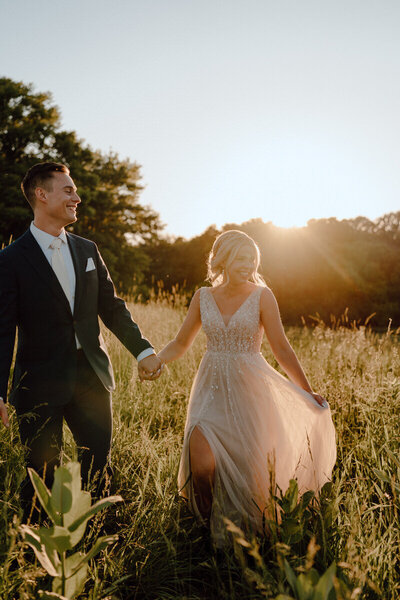 bride and groom walking in grass field