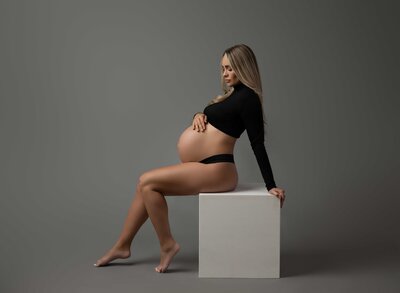 Pregnant Mom looking down at her belly, wondering what baby will look like. Photo taken by Jenni Nikki Photography in Woodstock GA