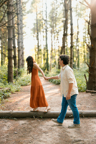 couple holds hands in woods during photoshoot