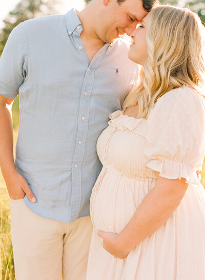 Mom snuggling her expectant belly lovingly during an outdoor maternity photography session at Joyner Park in Wake Forest NC. Photographed by Raleigh maternity photographer A.J. Dunlap Photography.