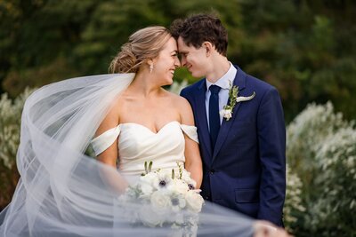Wedding veil blows in air with groom