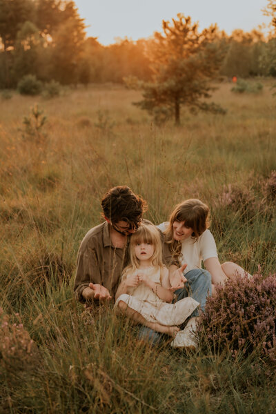 Gezin poseert in grasveld tijdens zonsondergang voor familie fotoshoot