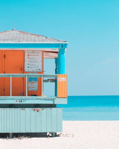 an old, closed down lifeguard stand against the ocean that's orange and blue for lifestyle photography socialfizz