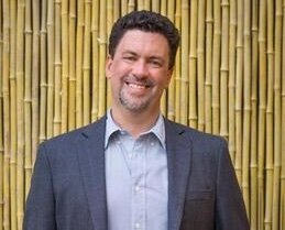 Headshot of Justin Shaw in a suit smiling at camera