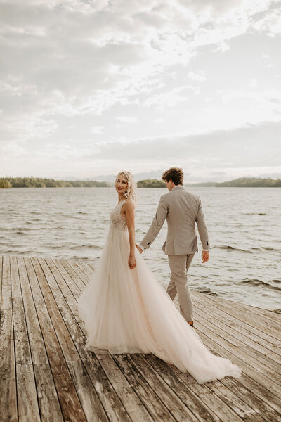 bride and groom holding hands on dock