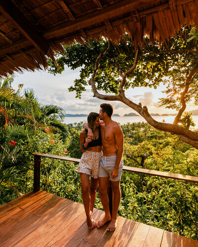 man and woman kissing with sunrise view