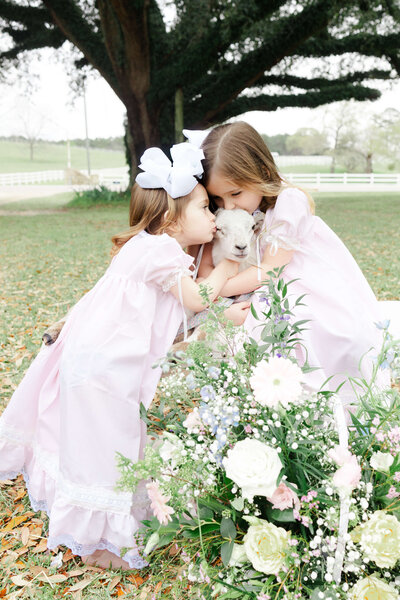 Siblings hugging lambs in a field