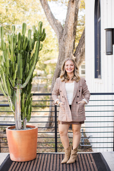 Samantha, wearing a blazer smiling next to a tall cactus