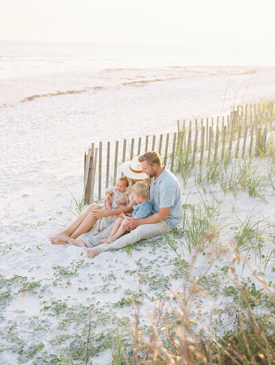Family of four sitting together on the beach with ocean in the background