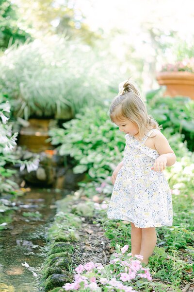 little girl looking at a creek in the middle of a garden