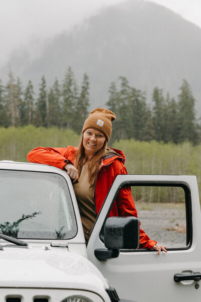girl stands on jeep door smiling