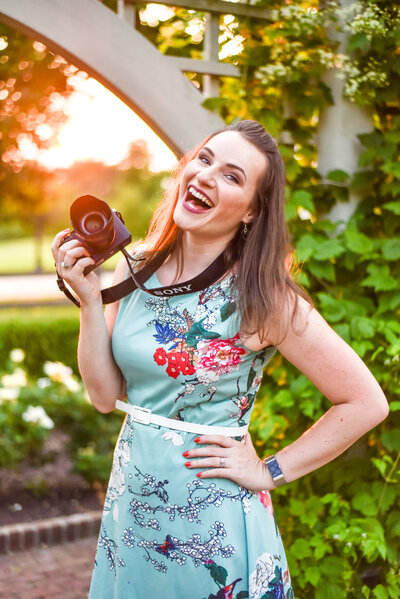 Amy Hord smiling big with her Sony camera in a colorful dress.