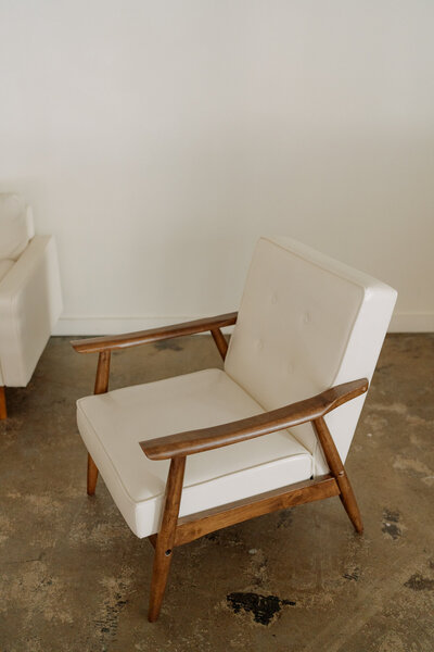 Minimalist white armchair with wooden frame in modern setting