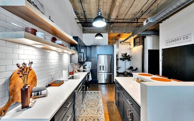 Kitchen with stainless steel appliances and subway tile in this three-bedroom, two-bathroom industrial modern loft condo in the historic Behrens building in downtown Waco, TX.
