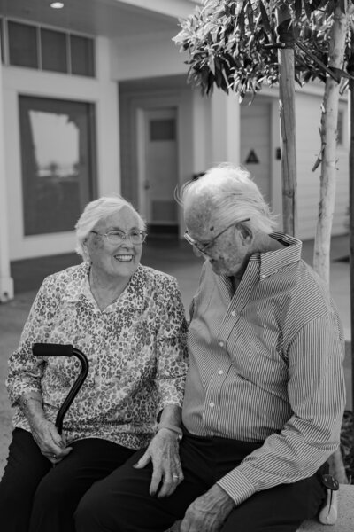 Two wedding guests laughing together, in black and white.