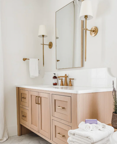 Elegant brass faucets pair with complementary brass sconces to lend function and style to the custom vanities