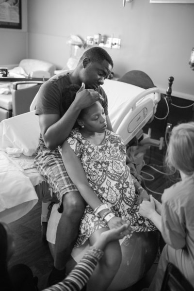 Laboring mother is supported by husband, friend and nurse during labor at northside atlanta