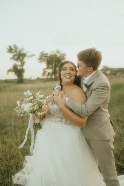 Married couple embraces in a field