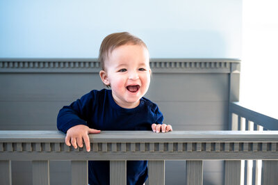 One year old standing in crib laughing