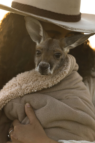 woman in a cowboy hat holding a kangaroo