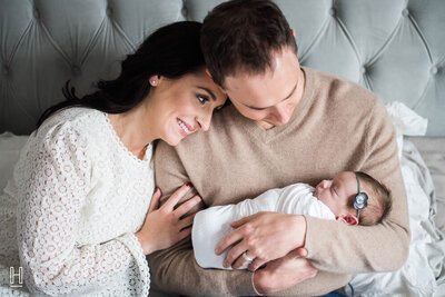 Woman and man holding their newborn child, looking at her lovingly.
