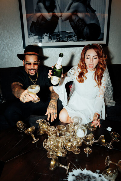 couple knocking over champagne tower in hotel room