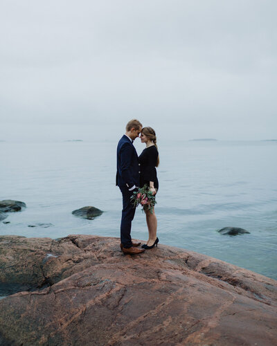 Eloping couple standing face to face foreheads touching at the cliff  in Helsinki in Finland